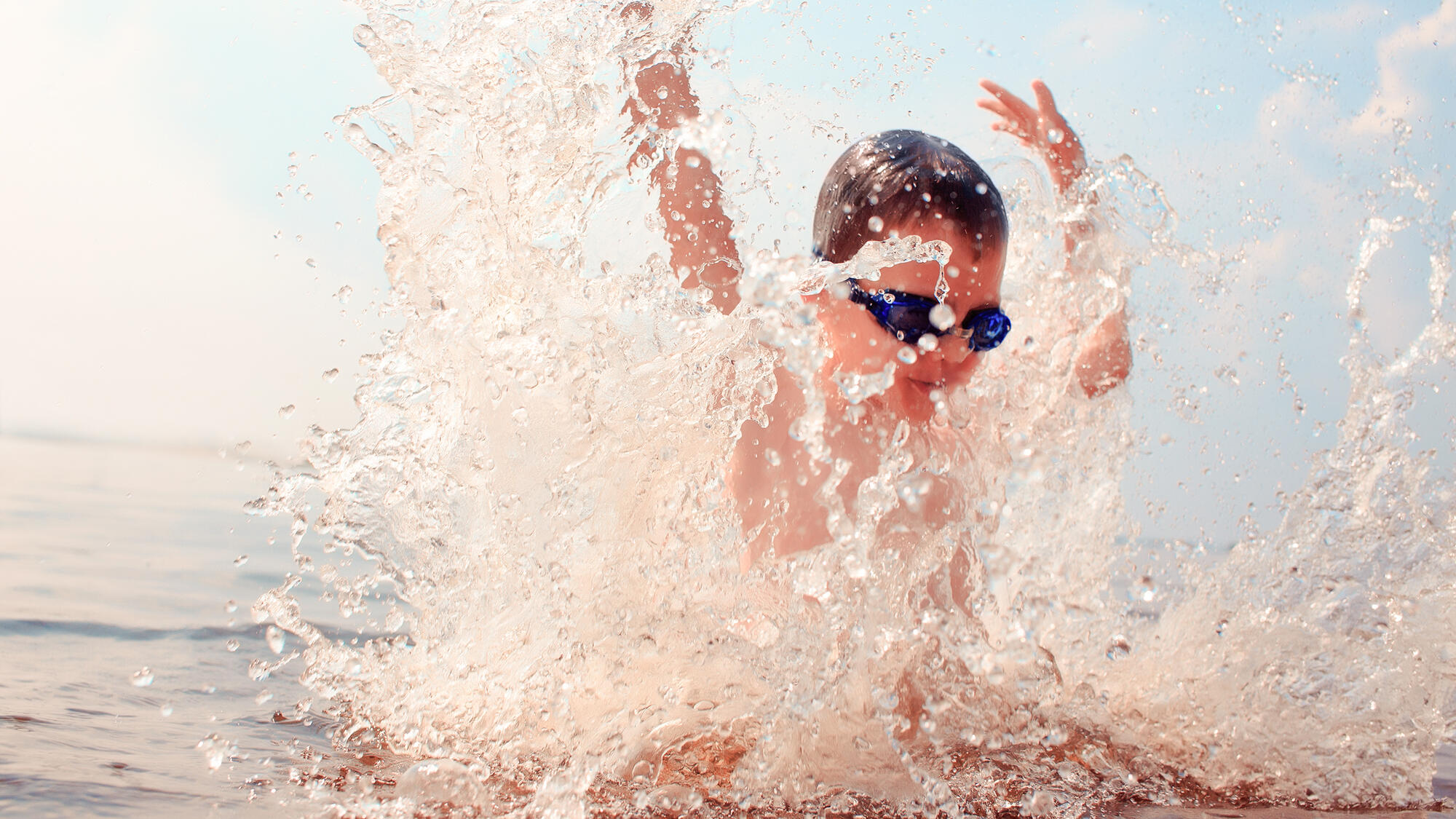 Small boy, playing in the water and wearing goggles
