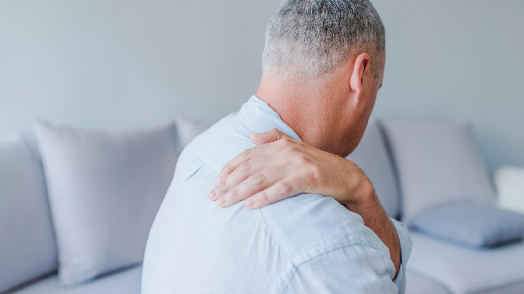 back of man holding painful shoulder